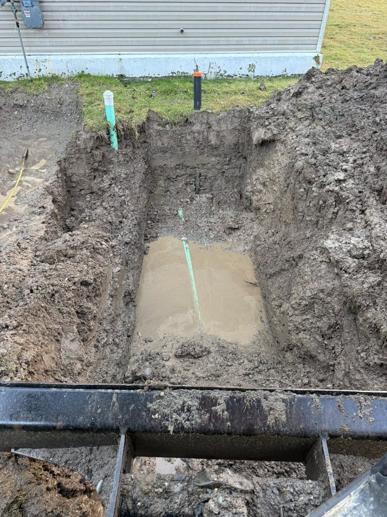 Excavated footing or utility trench with marked layout lines at a construction site.