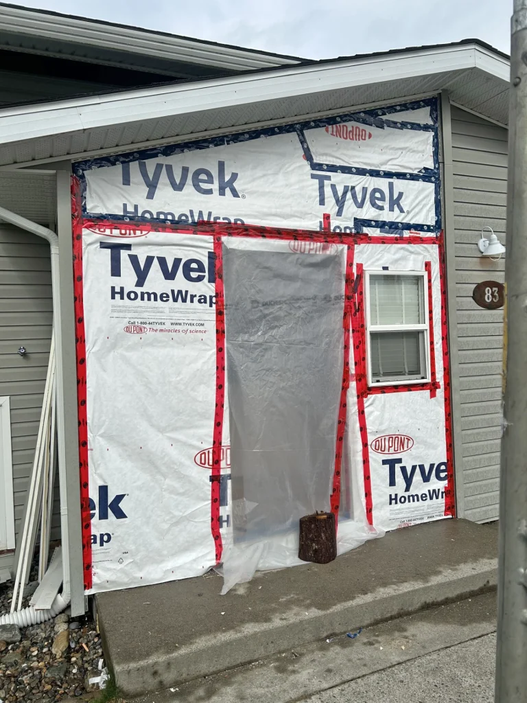 Exterior wall renovation with house wrap, flashing, and weatherproofing around entryway