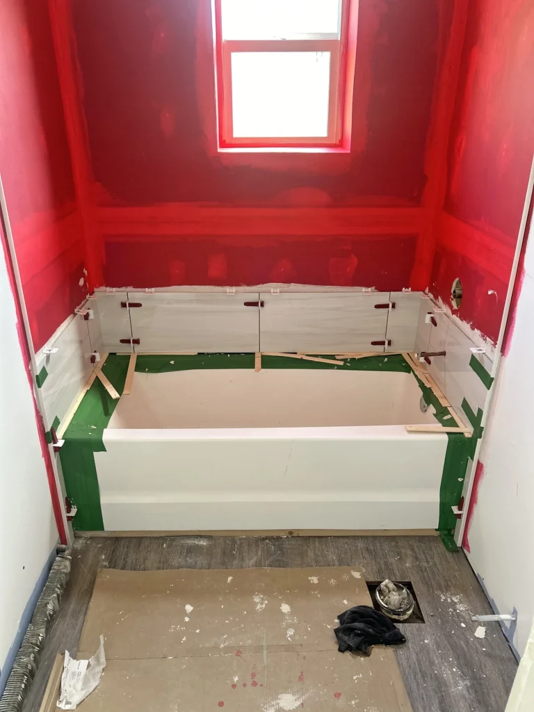 Bathroom renovation in progress with bathtub installation and tile work underway