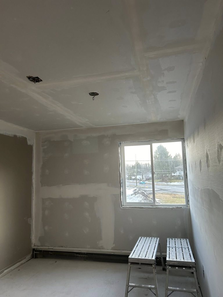 Interior room under construction with unfinished drywall and a window opening.
